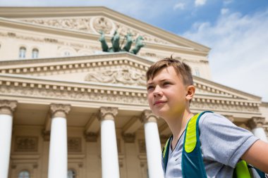 Boy stands in the background of the Bolshoi Theater  clipart