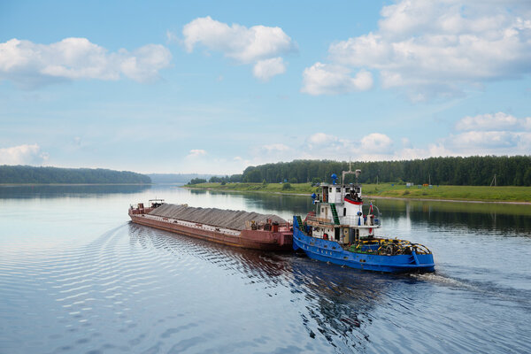 Tugboat moves barge on the Volga river 