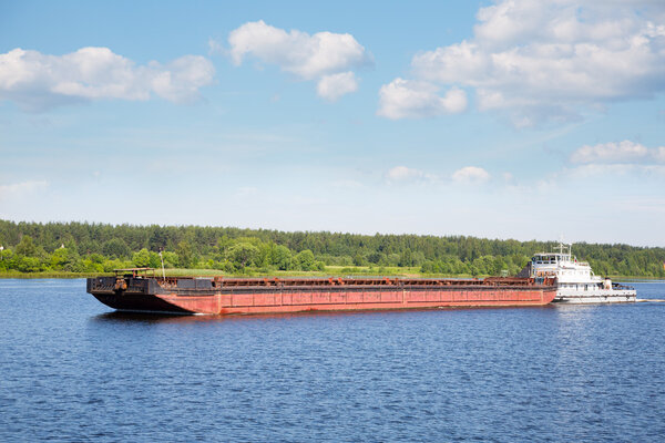 Tugboat moves cargo barge on the Volga river