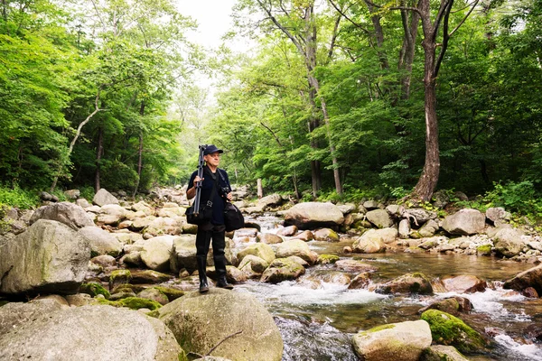 Fotografo con fotocamera viaggia attraverso il fiume di montagna — Foto Stock