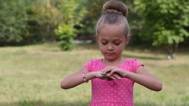 Chica bonita de seis años jugando con una pulsera para el brazo — Vídeo de stock