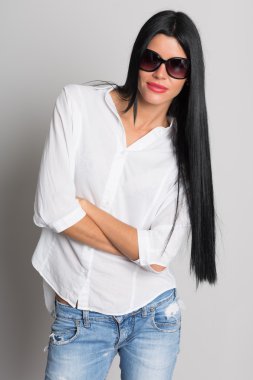 Gri bir arka plan üzerinde yırtık kot pantolon güzel kız