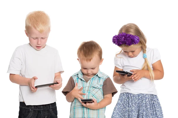 Küçük kardeşler ve kız kardeşi akıllı telefonlar kullanarak — Stok fotoğraf