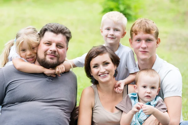 Retrato de familia feliz sentada en la hierba — Foto de Stock