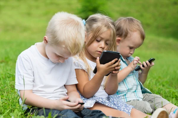 De gelukkige kinderen met behulp van smartphones — Stockfoto