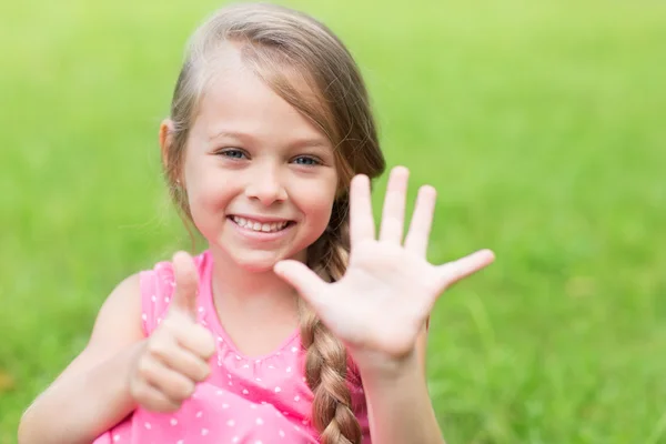 Lächelndes Mädchen zeigt Daumen hoch — Stockfoto