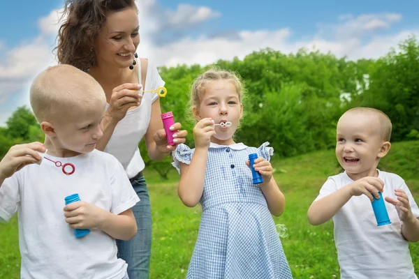 Madre con niños soplando burbujas — Foto de Stock