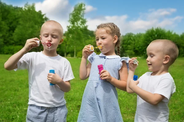 Lyckliga bröder och syster blåsa såpbubblor — Stockfoto