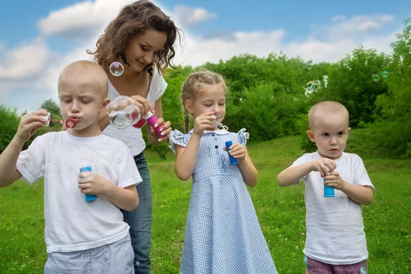 Mãe com filhos soprando bolhas — Fotografia de Stock