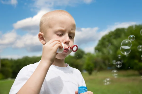 Jongen blaast zeepbellen in het park — Stockfoto