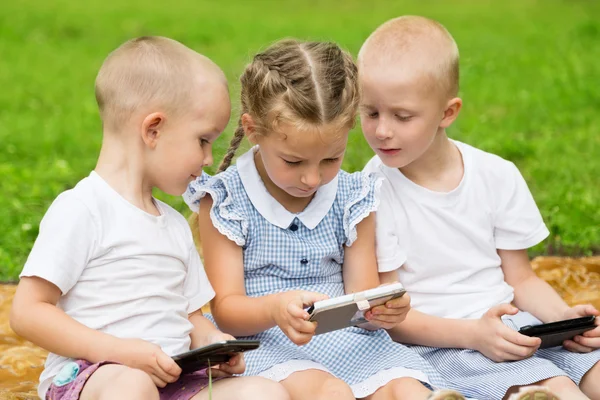 Lyckliga bröder och syster med smartphones — Stockfoto