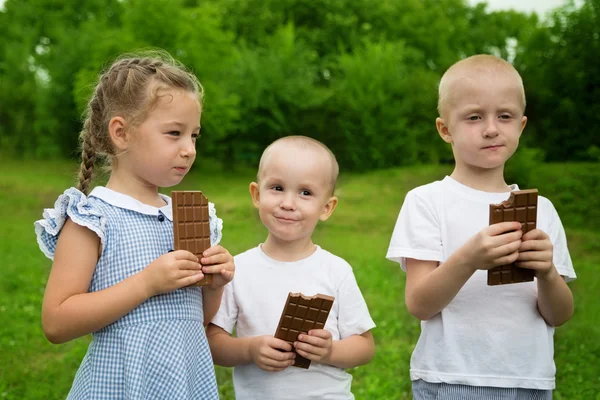 Joyful kids eating chocolate outdoors — Stock Photo, Image