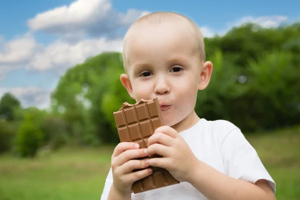 Gioioso ragazzino con piacere mangia cioccolato — Foto Stock