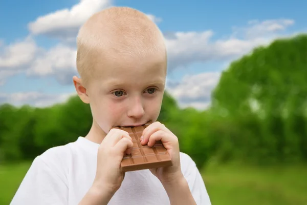 Kleine jongen met relish eten van chocolade — Stockfoto