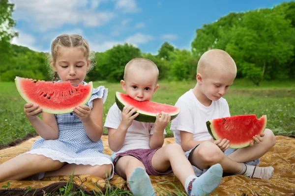 Joyful brothers and sister eating watermelon — Stock Photo, Image