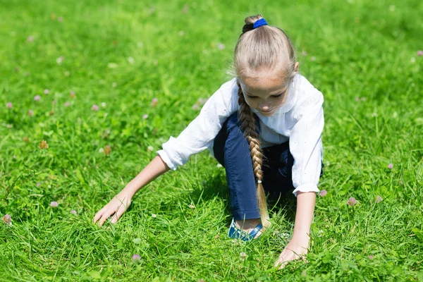 Joyful girl catches in the grass grasshopper — Stock Photo, Image