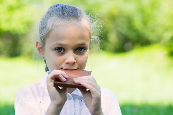 Fille avec plaisir manger une barre de chocolat . — Photo