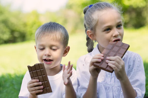 Children eating chocolate outdoors — Stock Photo, Image