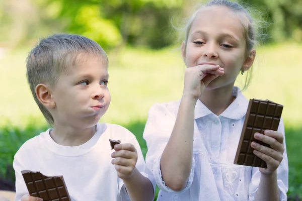 Brother and sister with relish eating chocolate — Stock Photo, Image