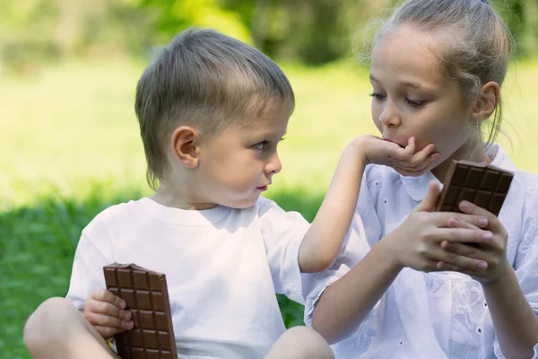 Brother and sister with relish eating chocolate — Stock Photo, Image