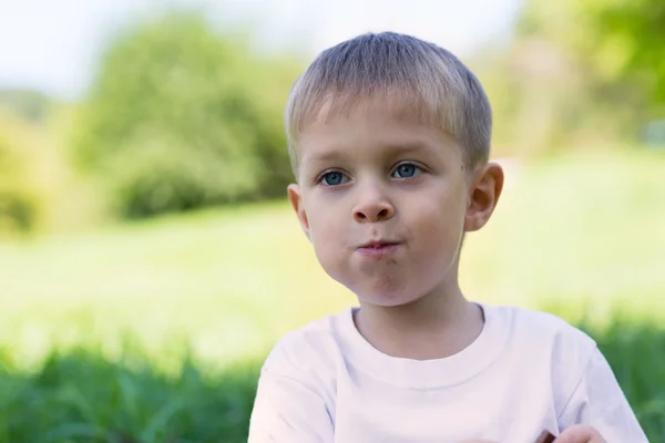 Glad ung pojke med munnen full av choklad — Stockfoto