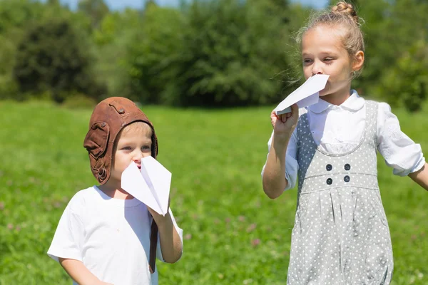 Niños jugando en el avión de papel al aire libre — Foto de Stock