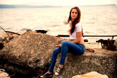 Eski bir iskelede oturup smartphone kullanan güzel kız