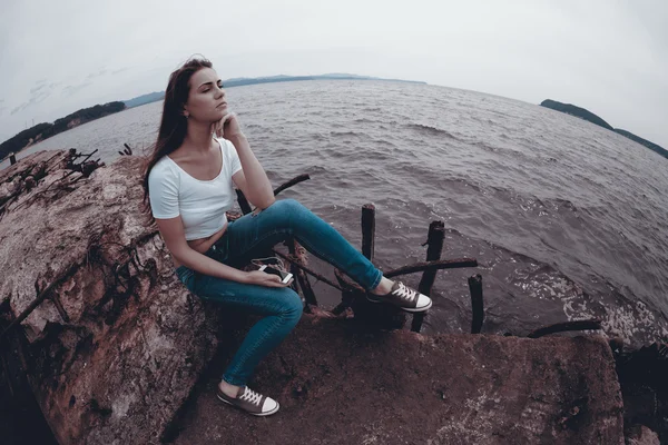 Fiatal lány ül egy régi mólón smartphone segítségével — Stock Fotó