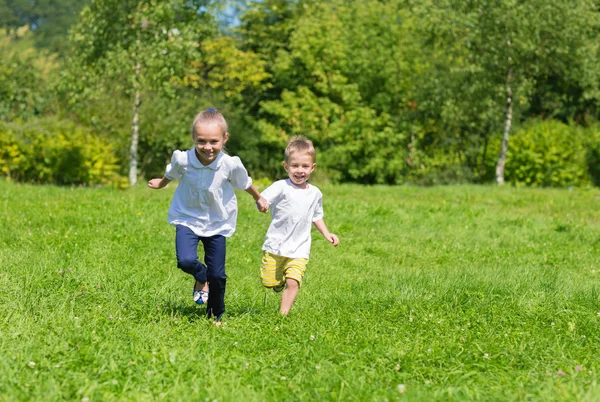 Fröhliche, fröhliche Kinder, die auf dem Rasen rennen — Stockfoto