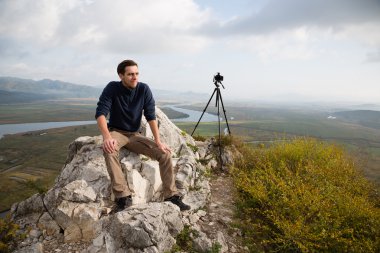 Portrait photographer sits on a mountaintop