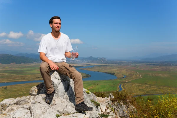 Hiker drinks water on top of the mountain — Stock fotografie