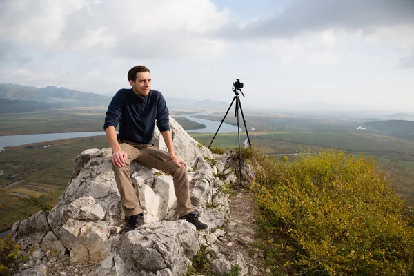 Portrait photographer sits on a mountaintop — Stock fotografie