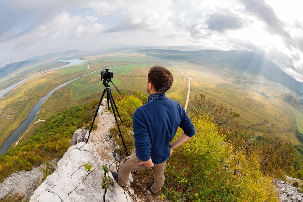 Photographer on top of the mountain takes on the camera