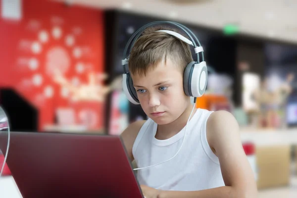 Мальчик в наушниках с ноутбуком — стоковое фото