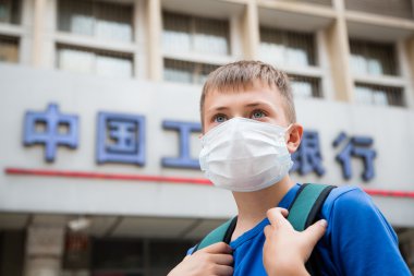  European boy in a protective mask on a street in Beijing