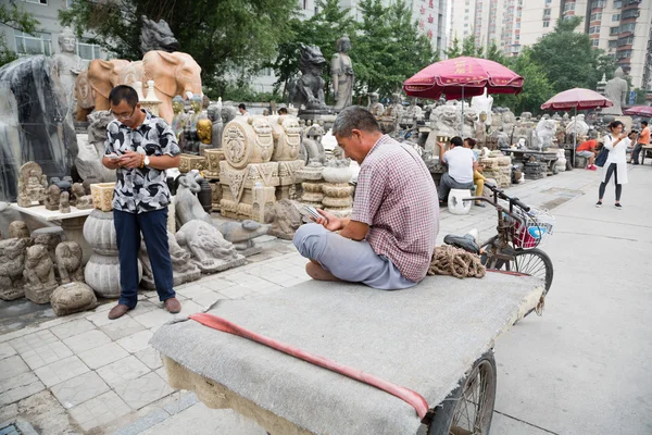Homem usa um celular enquanto o Panjiayuan Antique Market, Pequim — Fotografia de Stock