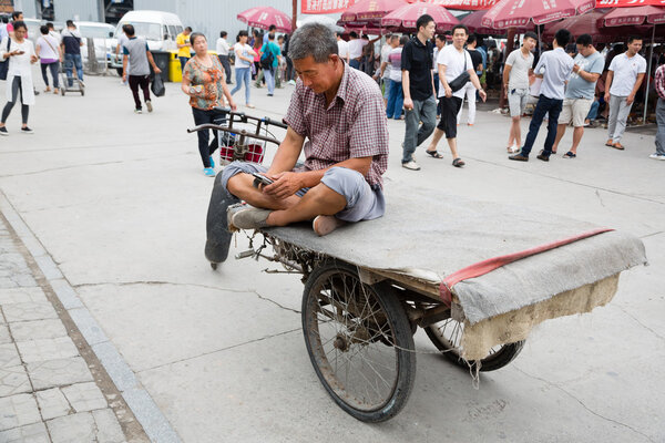 Man uses a smartphone while on Panjiayuan Antique Market, Beijin
