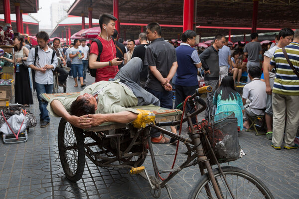 Man resting on a rickshaw of Panjiayuan Antique Market, Beijing