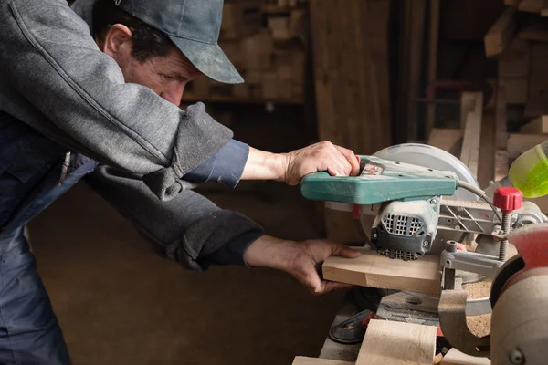 Carpinteiro serrar uma placa em uma máquina com uma serra de circulação — Fotografia de Stock