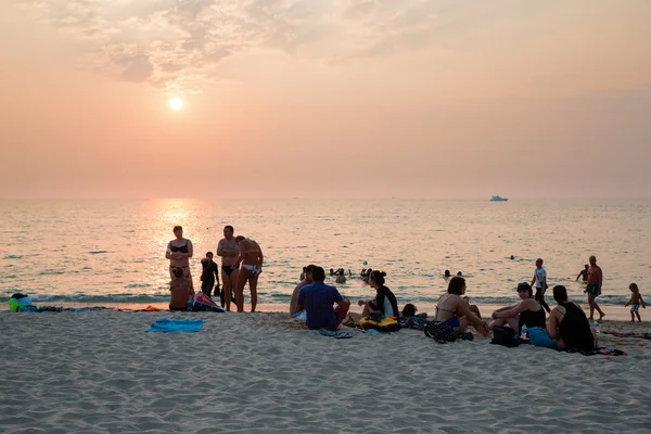 Menschen entspannen sich am Strand bei Sonnenuntergang — Stockfoto