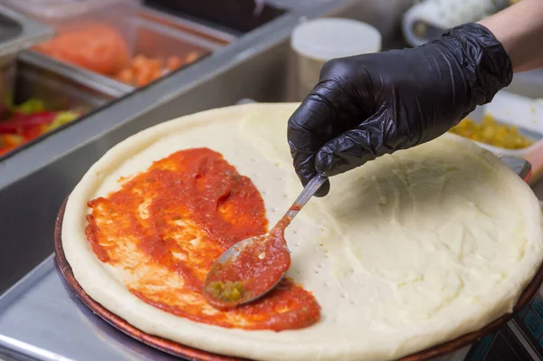 Μαγειρεύοντας Πίτσα Απλώνει Την Πρώτη Στρώση Ντομάτας Ένα Κουτάλι — Φωτογραφία Αρχείου