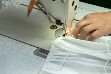 Bir dikiş fabrikası dikiş ekipmanları kullanarak koronavirüs için maske yapar..