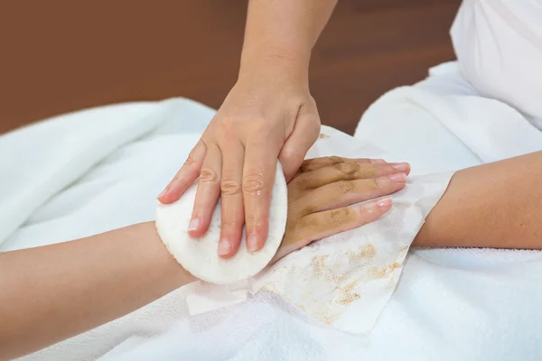 Terapeuta quitando la máscara de piel de la mano del cliente — Foto de Stock