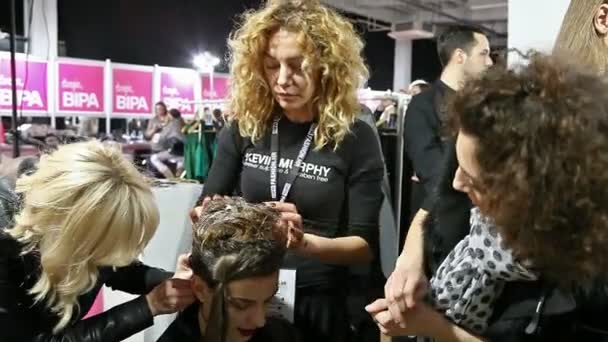 Профессиональные парикмахеры делают волосы модели за кулисами — стоковое видео