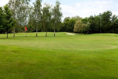 bir golf sahası üstünde kırmızı bayrak