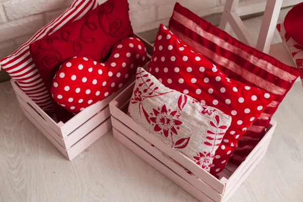 Diferentes almohadas rojas y blancas en cajas en el suelo . —  Fotos de Stock