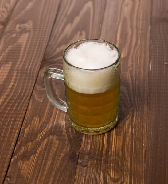 Frothy beer on table — Stock Photo, Image