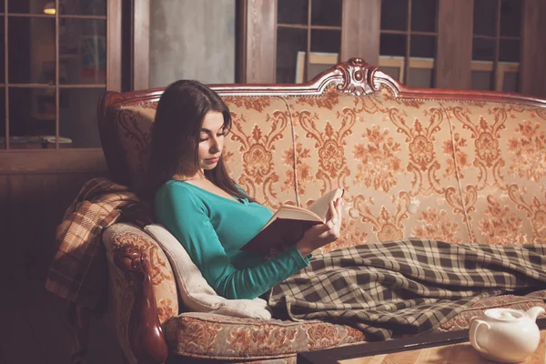 Mujer en sofá con libro rojo —  Fotos de Stock