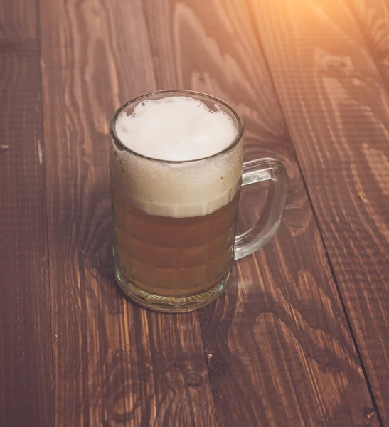 Frothy beer on table — Stock Photo, Image