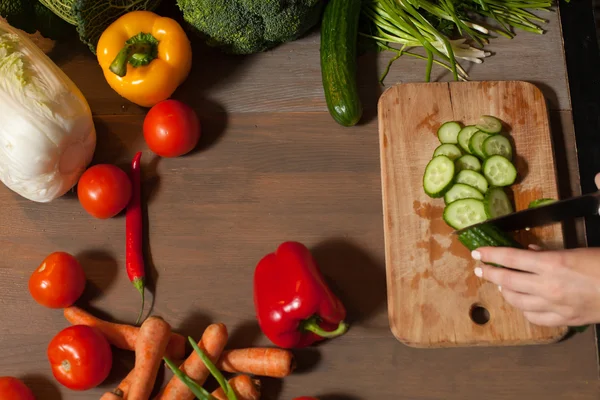 Komkommer in handen met mes — Stockfoto